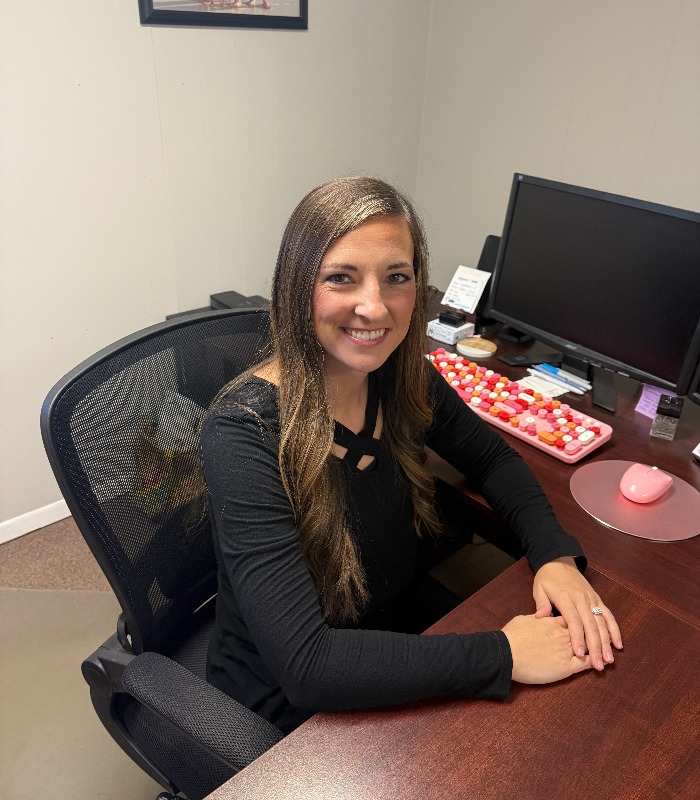 Meet Our Team - Professional and Welcoming Group at a Conference Table Faces the Camera, Team Leader Sitting on the Table with Arms Folded